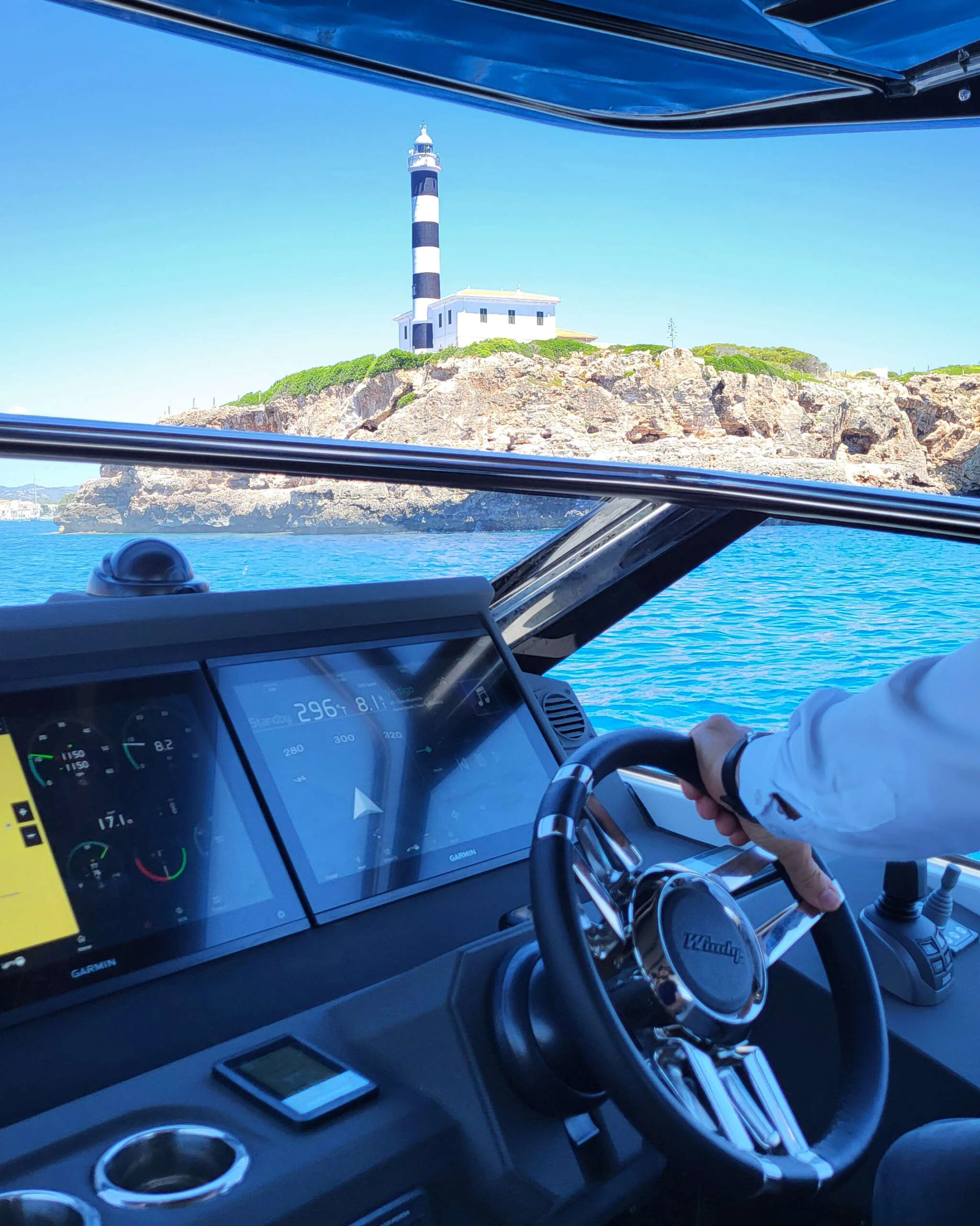 Poste de commande du Windy 40 Camira RS à Palma de Majorque, avec double écran Garmin et vue sur le phare depuis le bateau.