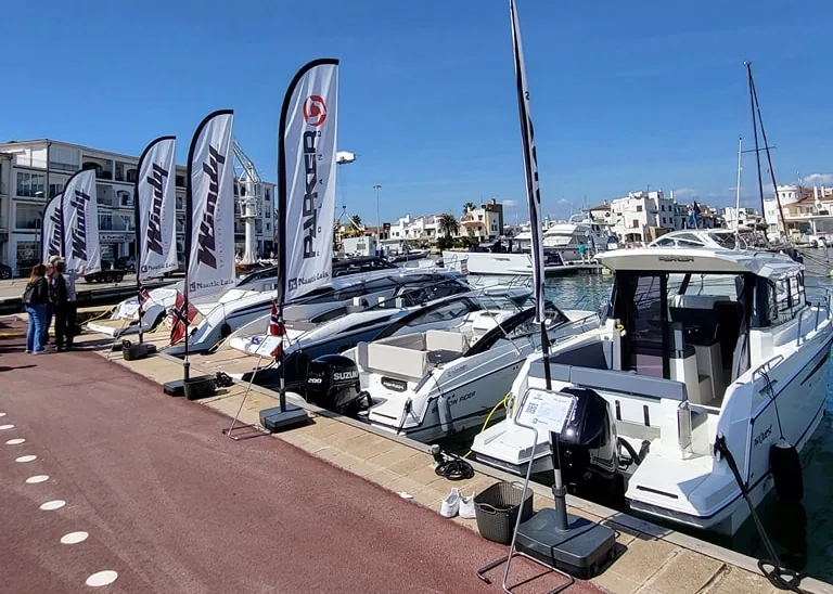 Boats from Nautic Luis displayed at the Fira del Vaixell d’Ocasió 2024, viewed from the pier with banners and outboard motors