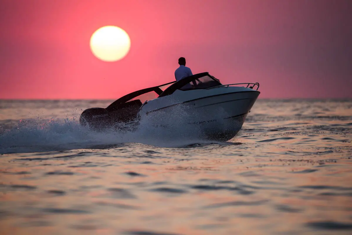 630 BR (10) Parker 630 Bow Rider naviguant de profil au coucher du soleil, avec une personne à bord et un sillage sur la mer