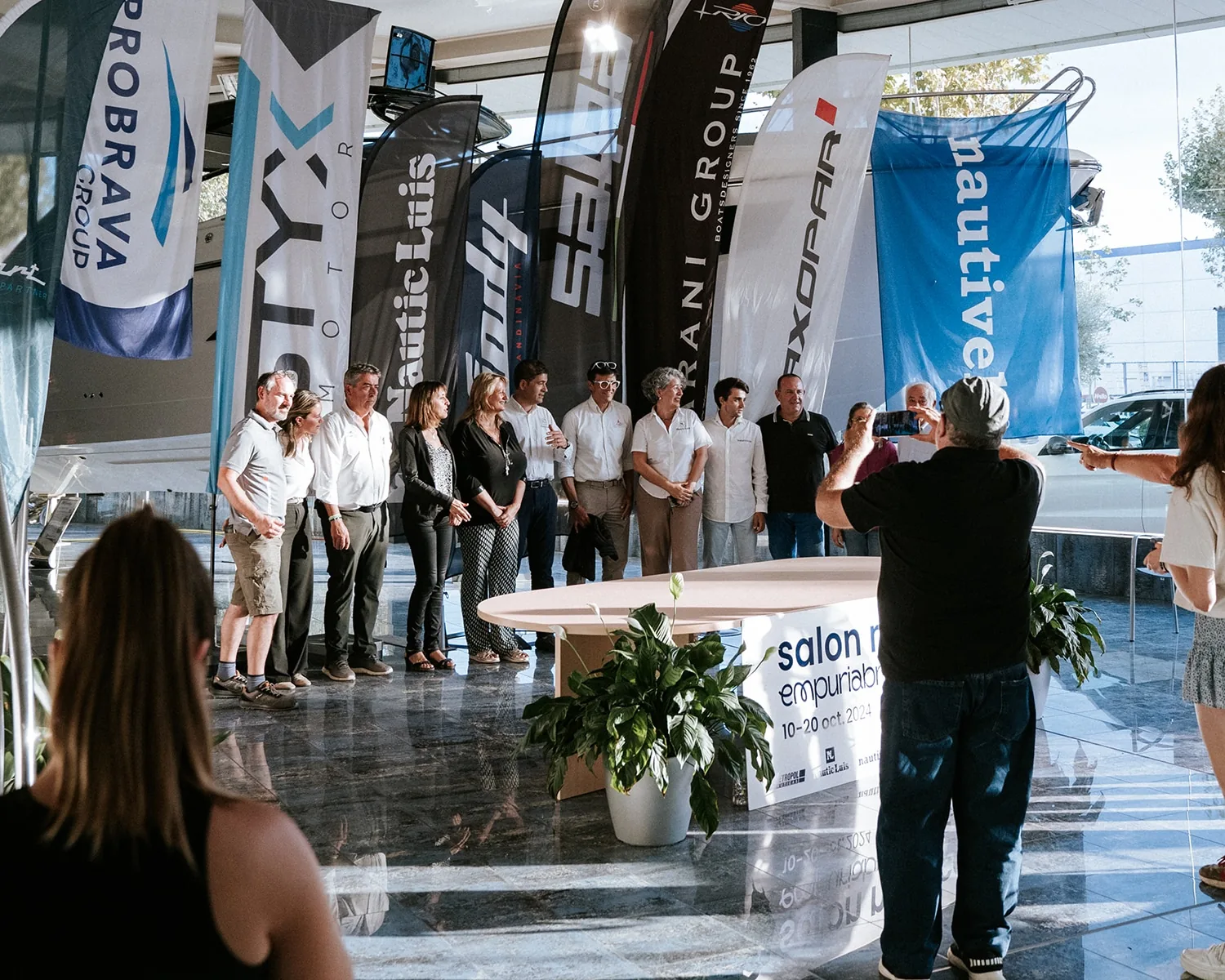Opening ceremony of the Empuriabrava Boat Show, with participants posing next to exhibitors and banners.
