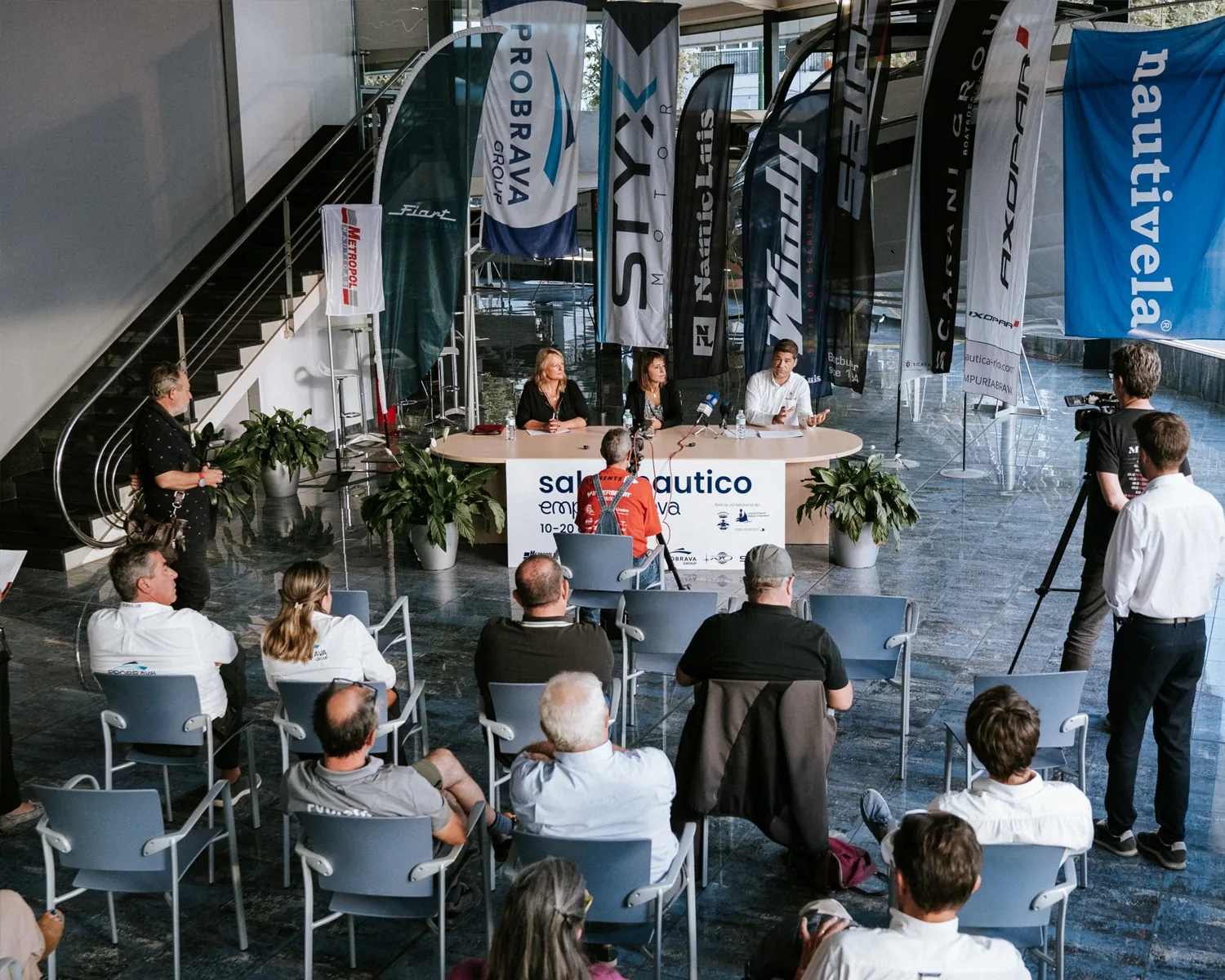 Presentation of the first Empuriabrava Boat Show, with speakers, audience, and flags of nautical exhibitors.