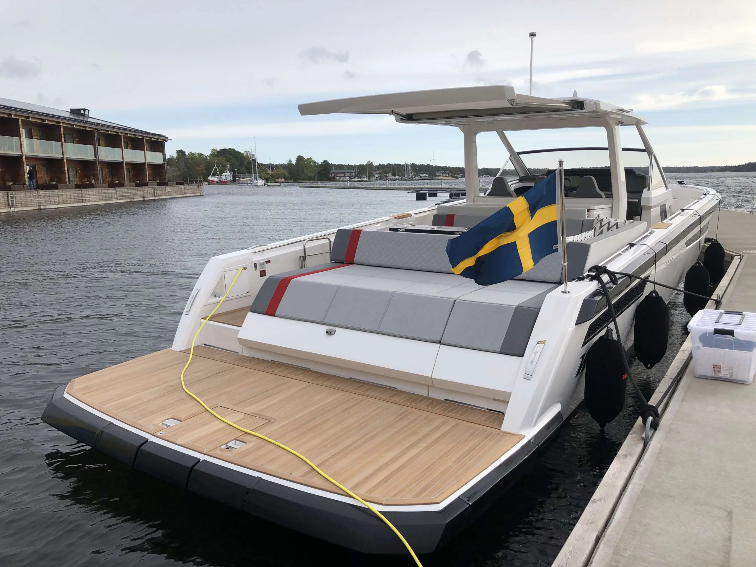 Windy SR 60 viewed from the stern, moored at the dock, with a teak deck, open lounge and Swedish flag.