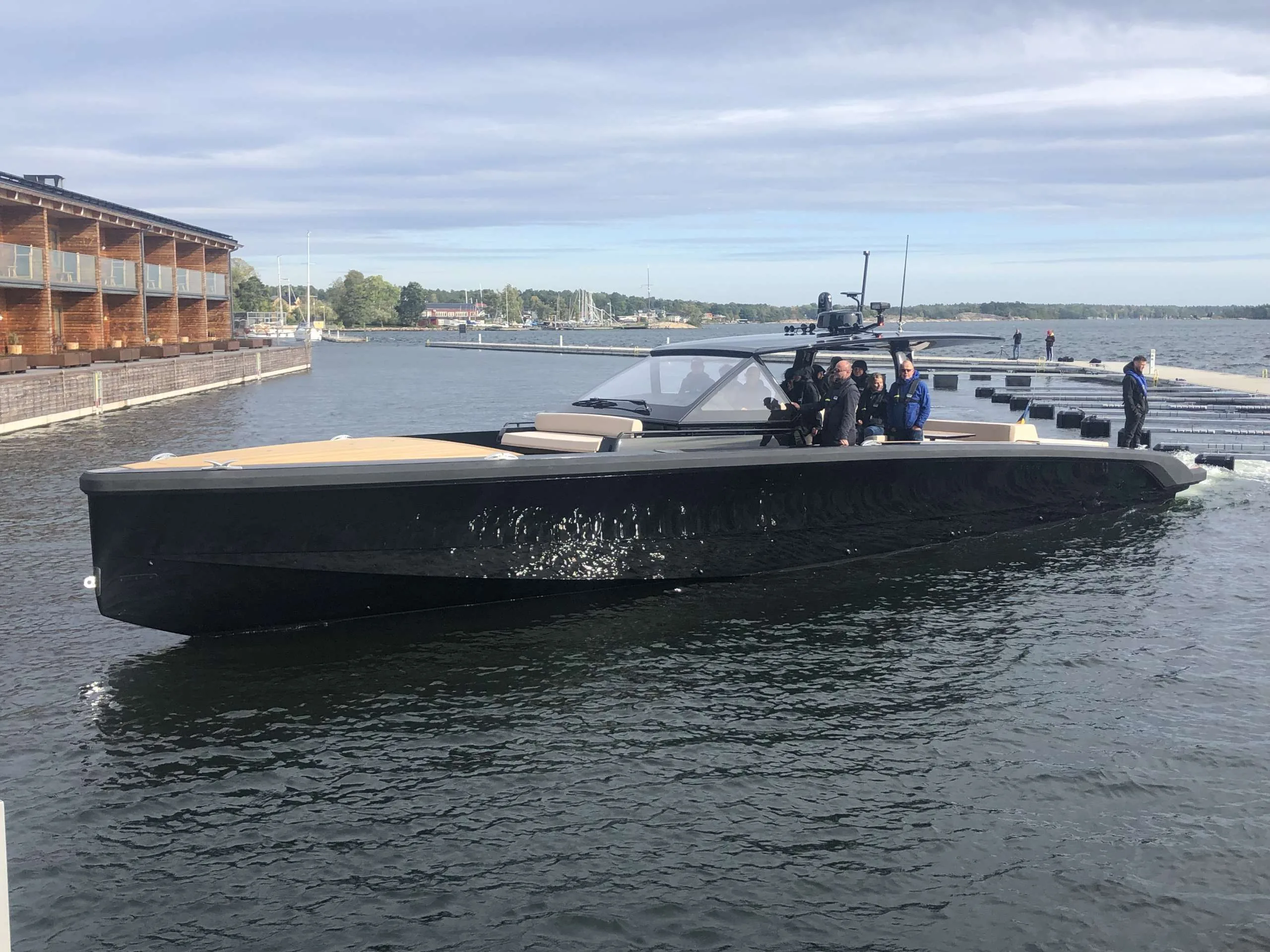 Exterior of the Windy SR 60 underway, side view, with passengers on board and coastline in the background.
