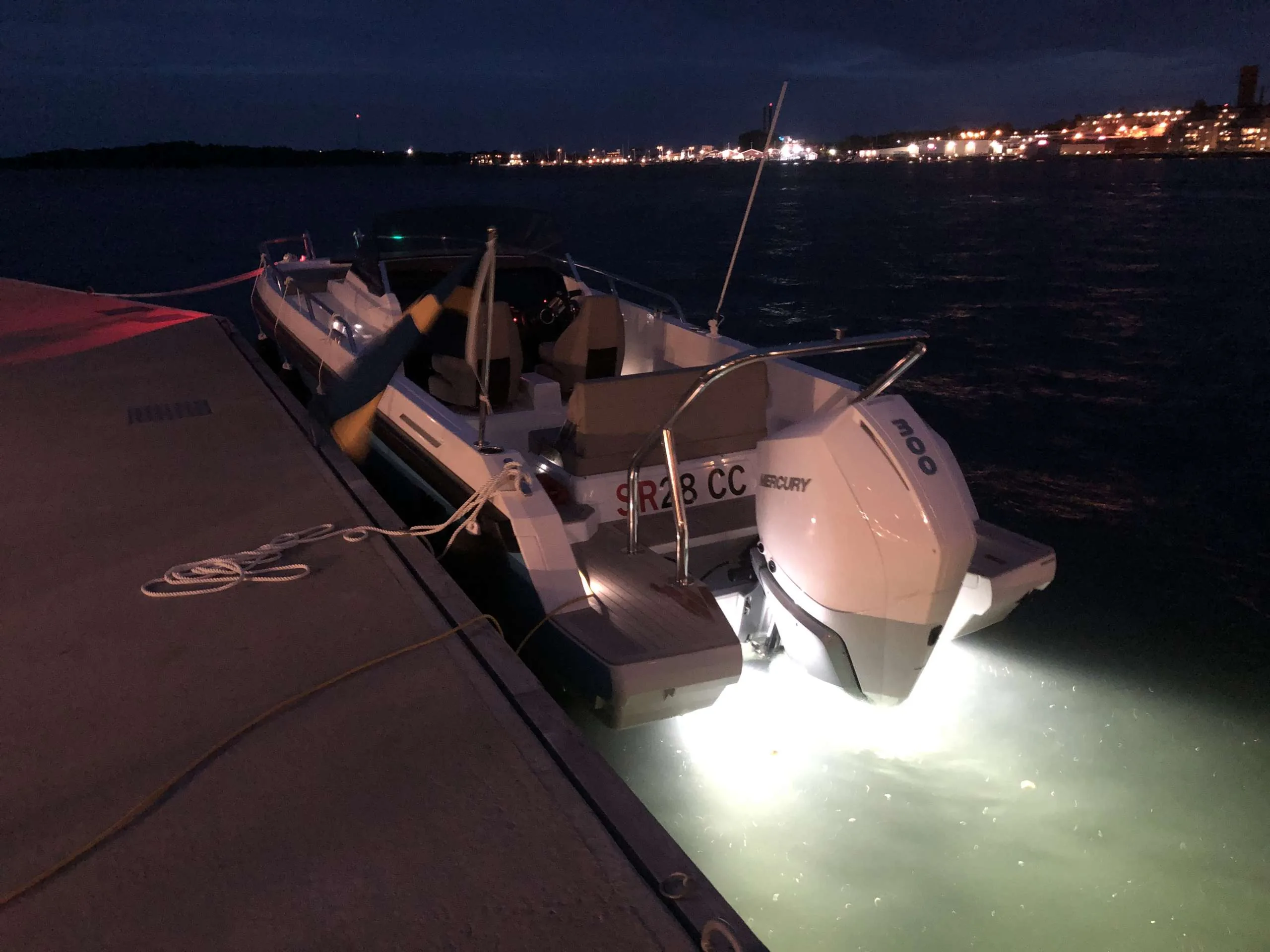 Windy SR 60 viewed from the stern, moored at night, with an outboard engine, deck and underwater lights.