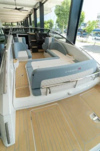 Intérieur du WINDY 27 SOLANO RS vu depuis la poupe, avec des sièges, une console de commande et un pont en teck.
