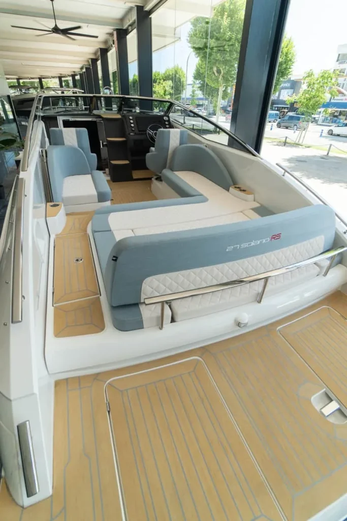 Intérieur du WINDY 27 SOLANO RS vu depuis la poupe, avec des sièges, une console de commande et un pont en teck.