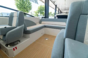 Intérieur du WINDY 27 SOLANO RS, avec des sièges face à face, un plancher en teck et une console de navigation.
