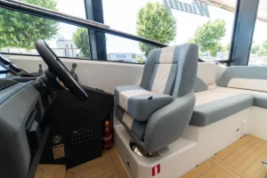 Intérieur du Windy 27 Solano RS, vue du poste de pilotage avec volant, siège du pilote et banquette latérale.