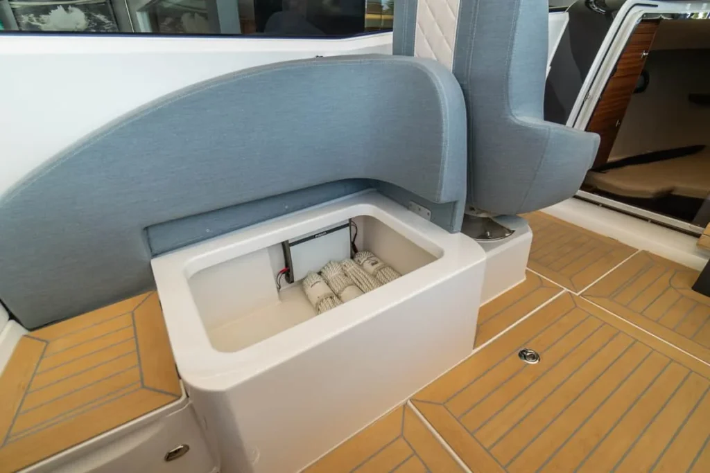 Windy 27 Solano RS : cockpit extérieur avec siège gris et compartiment de rangement ouvert sur un pont en teck synthétique