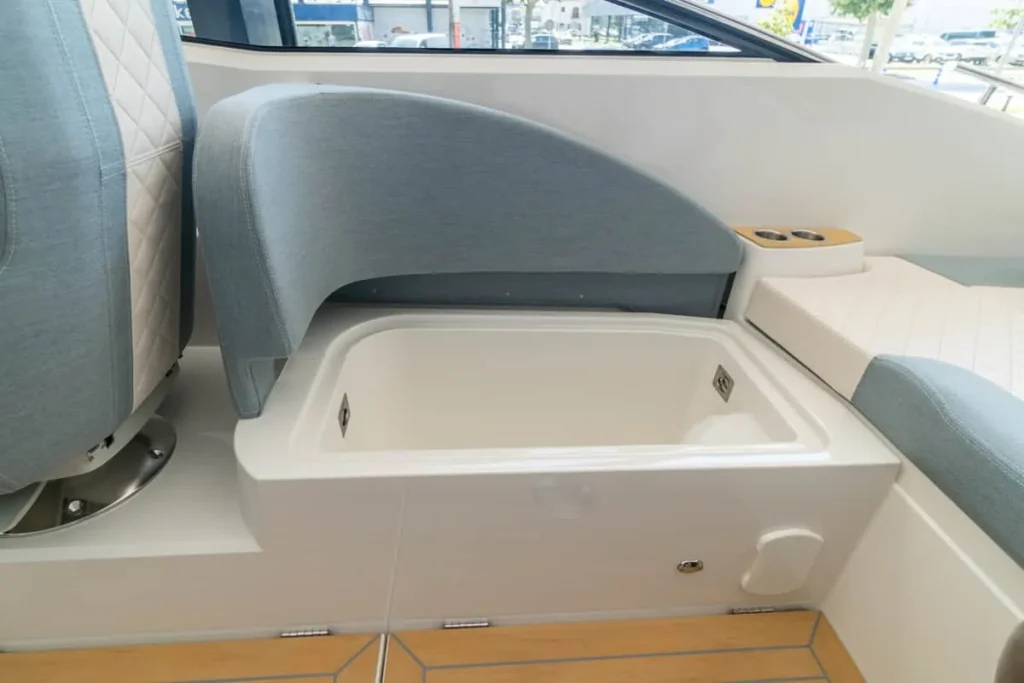 Intérieur du Windy 27 Solano RS avec compartiment ouvert et sièges rembourrés, vu de côté.