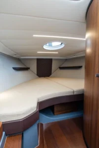 Intérieur du Windy 27 Solano RS, avec une couchette avant, une trappe zénithale, des étagères et des finitions en bois.
