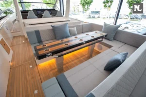 Interior del Windy SR44 Blackhawk, salón con sofás, mesa de madera, cojines y suelo de teca.
