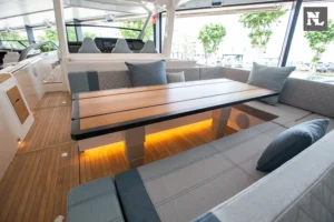 Interior del Windy SR44 Blackhawk con salón, mesa de madera, sofás tapizados e iluminación bajo los asientos.