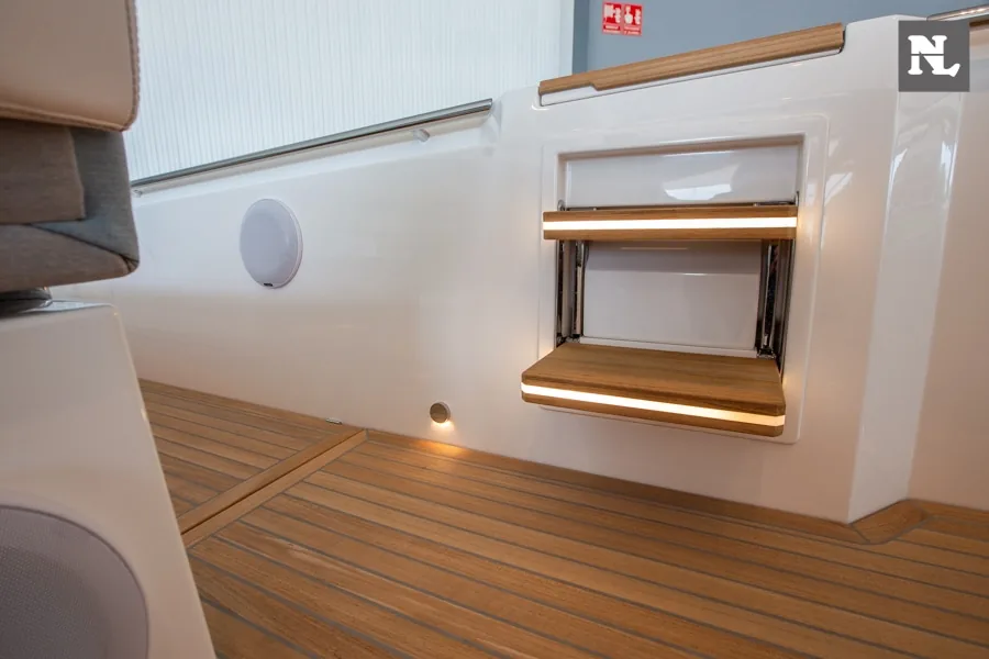 Windy SR44 Blackhawk, pasillo interior con suelo de teca, altavoz y escalera plegable iluminada.