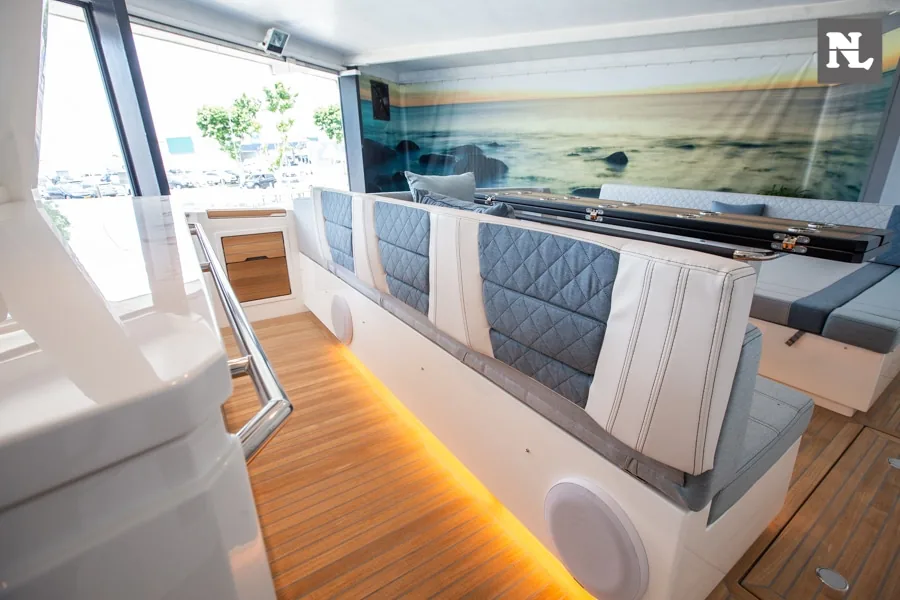 Interior del Windy SR44 Blackhawk, vista hacia salón con sofá tapizado, mesa, ventanales y suelo de madera.