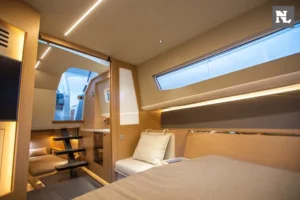 Interior del Windy SR44 Blackhawk: camarote con cama, sofá, escalera y ventanales laterales.