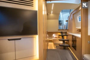 Interior del Windy SR44 Blackhawk 26, con televisor, mesa, bancos, cocina y pasillo vistos desde el salón.