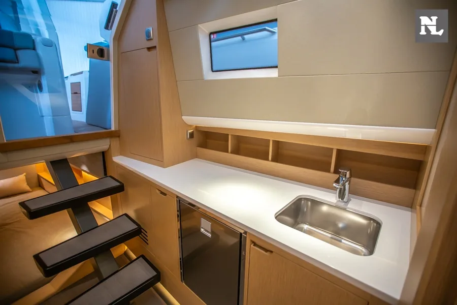 Interior de la cocina del Windy SR44 Blackhawk 29, con fregadero, encimera, armarios y escalera lateral.
