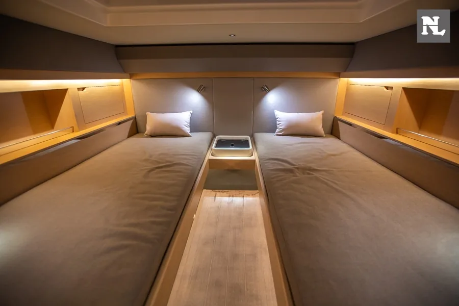 Interior del Windy SR44 Blackhawk con dos camas individuales, pasillo central y armarios laterales iluminados.