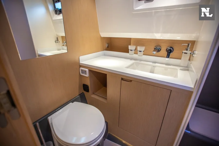 Baño interior del Windy SR44 Blackhawk, con lavabo, espejo, inodoro y muebles de madera.