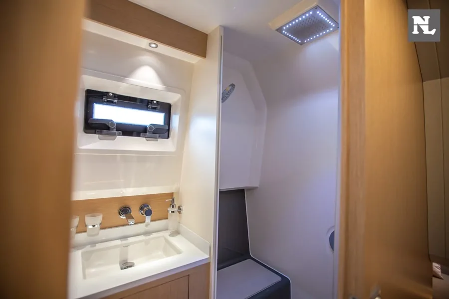 Interior del Windy SR44 Blackhawk 34, baño con lavabo, grifería, espejo, armario y ducha con iluminación LED.