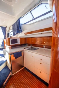 Pantryküche der gebrauchten Cranchi Atlantique 40 in Empuriabrava – Nautic Luis, mit L-förmiger Arbeitsplatte, Mikrowelle und Holzmöbeln