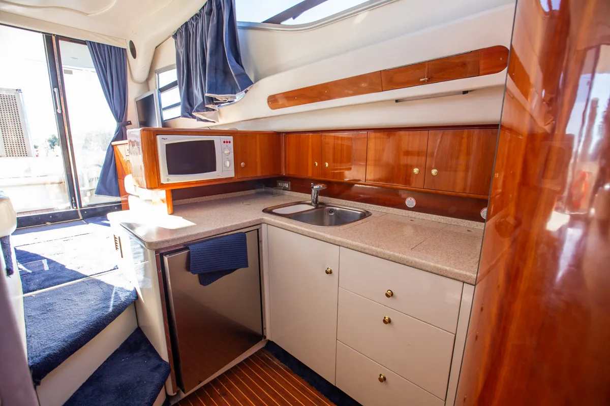 Cranchi Atlantique 40 – Galley vista lateral Pantryküche der gebrauchten Cranchi Atlantique 40 in Empuriabrava – Nautic Luis, Seitenansicht mit Arbeitsplatte, Mikrowelle und Kühlschrank