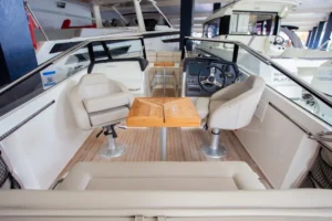 Interior del Draco 27 R Sport visto desde popa, con asientos, mesa de madera, puesto de mando y cabina.