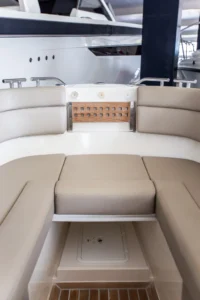 Interior de Draco 27 RSport, vista de proa con asientos tapizados, panel de interruptores y escotilla en el suelo