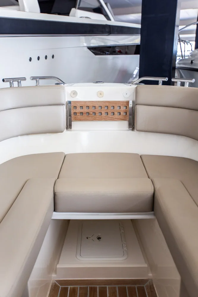 Interior de Draco 27 RSport, vista de proa con asientos tapizados, panel de interruptores y escotilla en el suelo