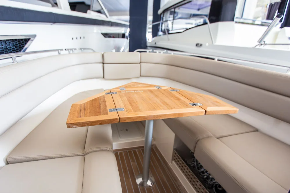 Draco 27 RS: interior de proa abierta con mesa de madera y asientos tapizados en U