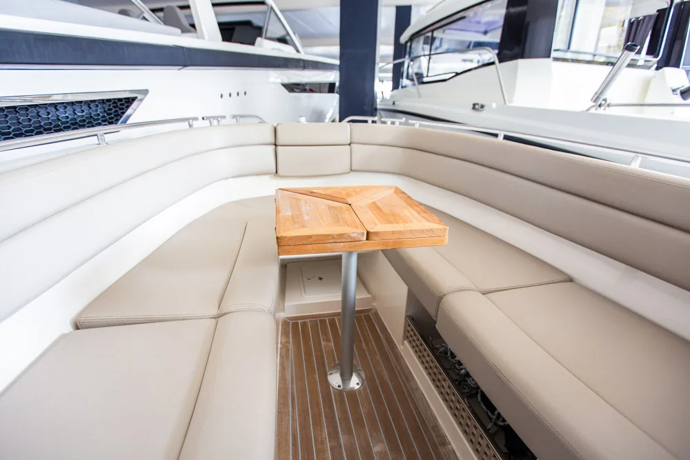 Interior de proa del Draco 27 RS, con asientos enfrentados, mesa de madera abatible y suelo de teca.