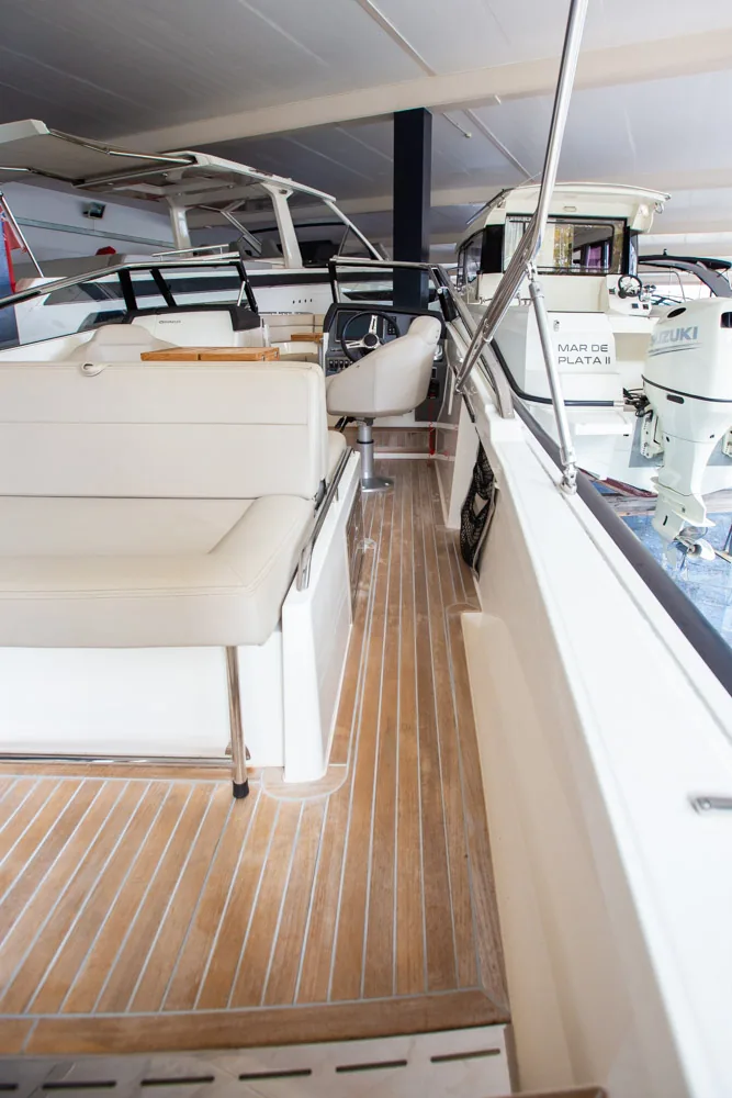 Draco 27 RSport: pasillo de estribor con cubierta de teca, asiento, consola y motor fueraborda visible