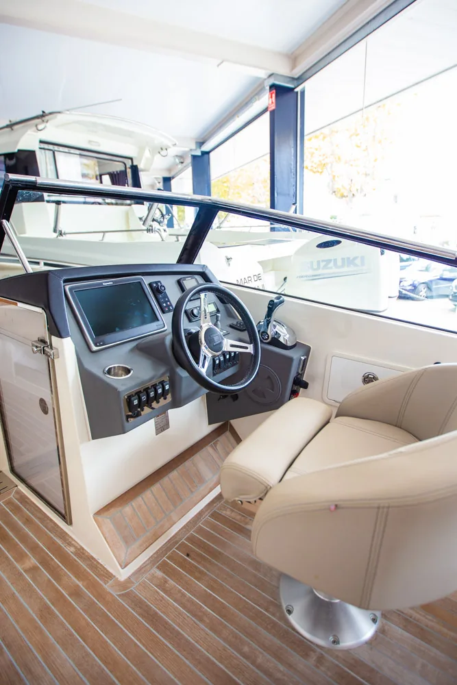 Interior del Draco 27 RSport, puesto de piloto con volante, pantalla, mandos, asiento y suelo de teca.