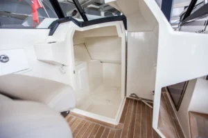 Interior del Draco 27 R Sport, vista desde la bañera hacia la cabina con litera y suelo de teca.