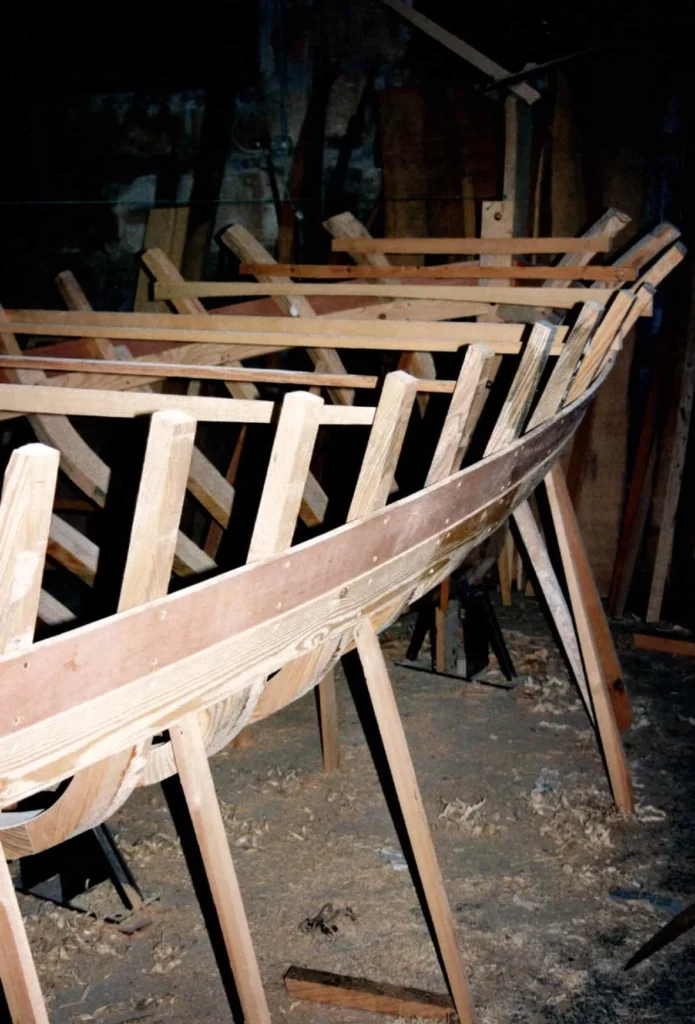 LLAUT 32P im Bau, Seitenansicht des Holzrumpfs und seiner Spanten in einer Werkstatt.