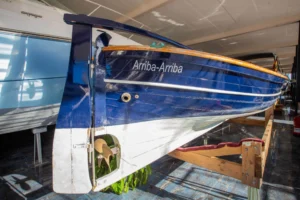 LLAUT 32P von achtern im Innenbereich gesehen, mit blauem Rumpf, sichtbarem Propeller und dem Namen „Arriba-Arriba“.