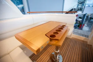 Marex 360 Cabriolet Cruiser, table en bois avec porte-gobelets dans le cockpit, sièges blancs et pont en teck.