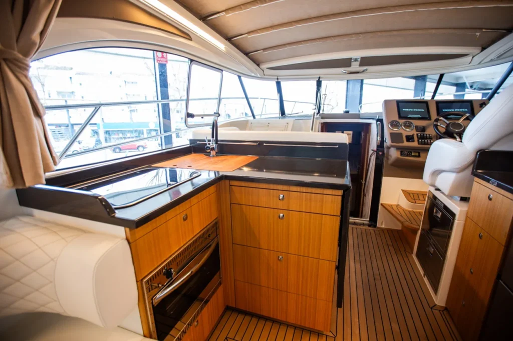 Intérieur du Marex 360 Cabriolet Cruiser, vue sur la cuisine et le poste de pilotage, avec des placards et des sièges.