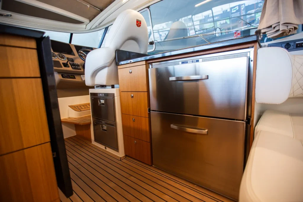 Intérieur du Marex 360 Cabriolet Cruiser, avec cuisine, réfrigérateur, sièges et plancher en teck vus depuis la poupe.