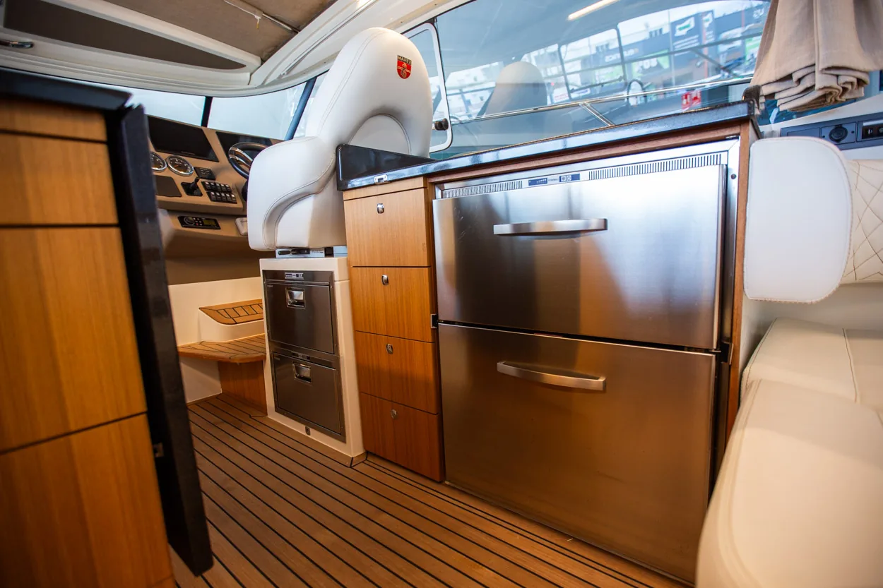 Buddy_M360-15 Intérieur du Marex 360 Cabriolet Cruiser, avec cuisine, réfrigérateur, sièges et plancher en teck vus depuis la poupe.