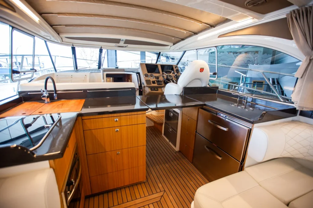 Intérieur du Marex 360 Cabriolet Cruiser, avec cuisine, table, salon et poste de pilotage, vu depuis la poupe.