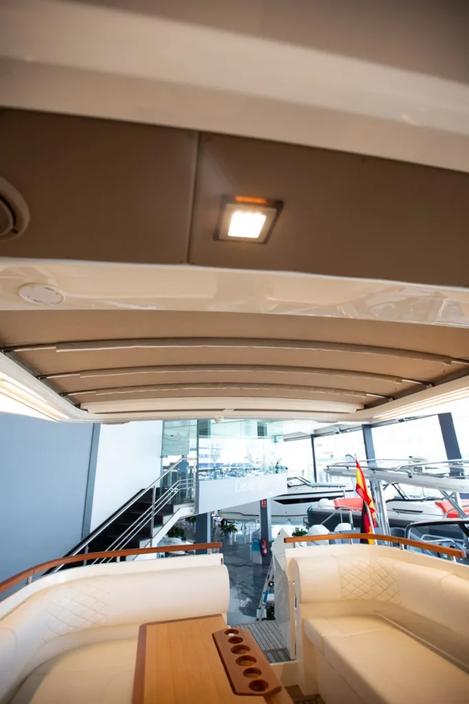Intérieur du Marex 360 Cabriolet Cruiser, avec des sièges rembourrés, une table en bois et un toit ouvrant, vu depuis la proue.