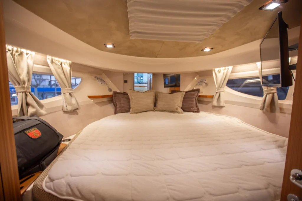 Intérieur du Marex 360 Cabriolet Cruiser, cabine avec lit double, fenêtres latérales, rideaux et écrans.