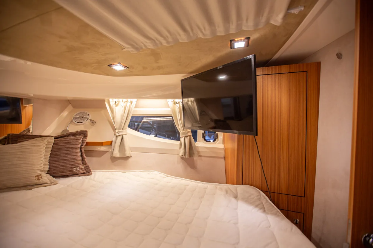 Buddy_M360-24 Intérieur du Marex 360 Cabriolet Cruiser : cabine avec lit, télévision, fenêtre avec rideaux et armoire en bois.
