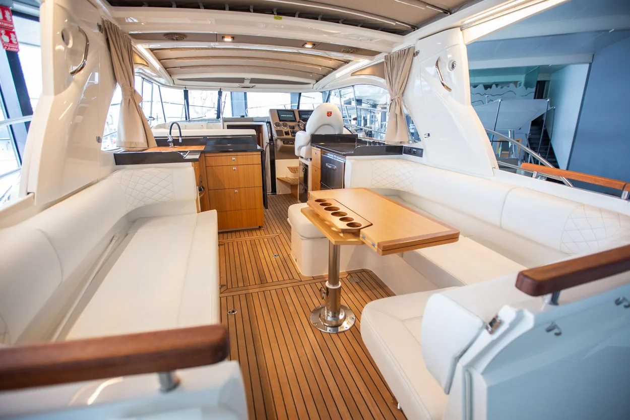 Buddy_M360-7 Intérieur du Marex 360 Cabriolet Cruiser, vue vers la cuisine et le salon avec canapés, table et plancher en teck