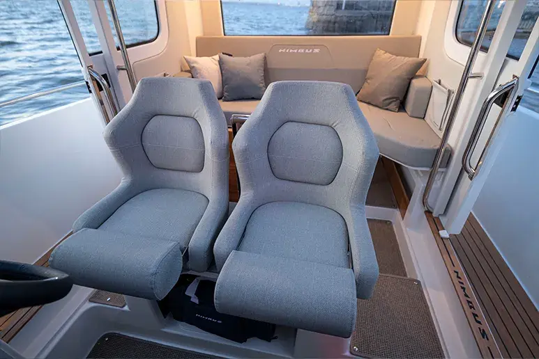 Interior del Nimbus C9 con dos asientos de navegación y sofá en la cabina de proa.