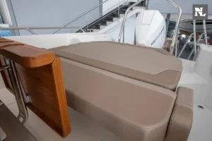 Nimbus T8 Taupé, vista de la bañera con asientos tapizados, mesa de madera abatible y motor fueraborda visible
