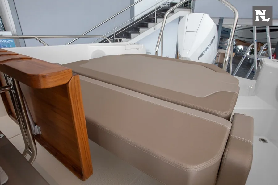 Nimbus T8 Taupé, vista de la bañera con asientos tapizados, mesa de madera abatible y motor fueraborda visible