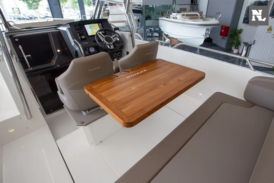 Interior del Nimbus T8, vista hacia el puesto de gobierno, mesa de madera, asientos y consola de navegación.